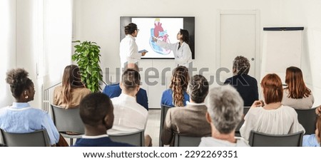 A team of Asian doctors illustrates results of their research conducted on the human heart. The audience consists of other medical specialists and major representatives of pharmaceutical companies.  Royalty-Free Stock Photo #2292269351