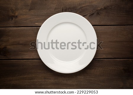Empty white plate on wooden table close up
