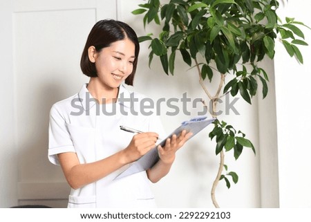 A woman who is a medical worker writing a chart Royalty-Free Stock Photo #2292292103