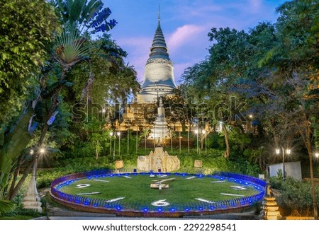 In Wat Penh gardens,a gift from China,covered in green grass,a large working clock,beneath the hilltop pagoda of Wat Phnom,a prominent city landmark,next to the circular pathway. Royalty-Free Stock Photo #2292298541