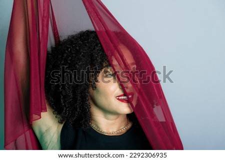 Beautiful young woman with red cloth suspended around her body. studio portrait