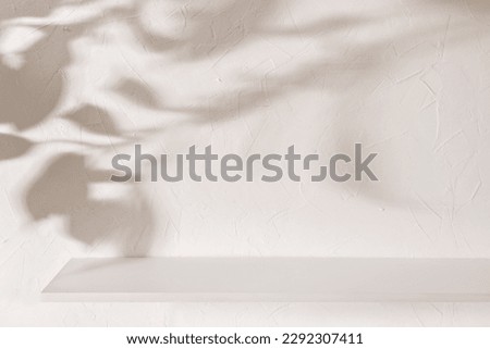 Empty shelf on a beige textured plaster wall background with aesthetic floral sun light shadows, product stand or podium design template for business branding advertisement, mockup with copy space