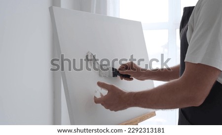 The artist creates a picture on a white canvas using plaster. 