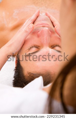 Beautician applying moisturizer man's face