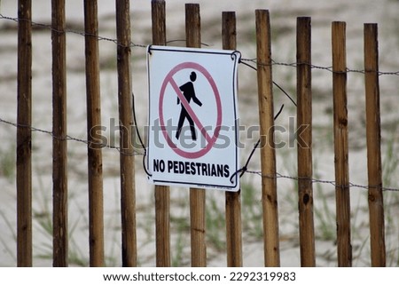A sign attached to a wooden fence that says "No Pedestrians".