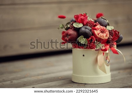 Flower composition with apples and pomegranate in white box on wooden  step