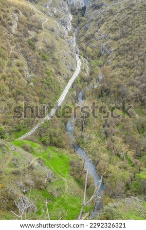 Natural Cliff In Serbia isolated during spring with river and train track.

A peaceful mountain pass viewed from high above, showcasing the stunning beauty of nature without a single person in sight.