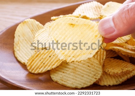 A lot of potato chips on a wooden plate Royalty-Free Stock Photo #2292331723