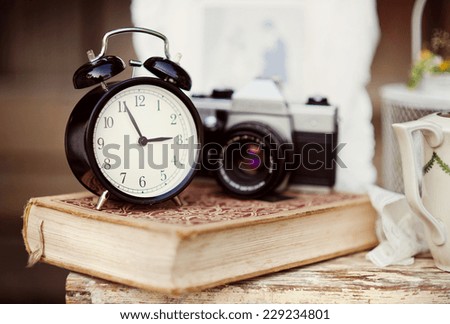 Group of objects on vintage wooden table. old alarm clock, retro camera, book