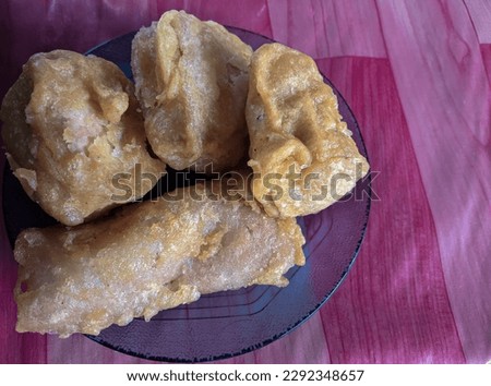 close up of fried tofu and risol with vegetable filling. photo against red and pink checkered background.