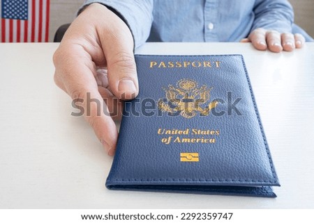 a man's hand gives an American passport. Migration Service, document verification. Royalty-Free Stock Photo #2292359747