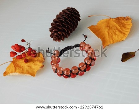Hippie orange bracelet and yellow leafs. Orange bracelet on a white