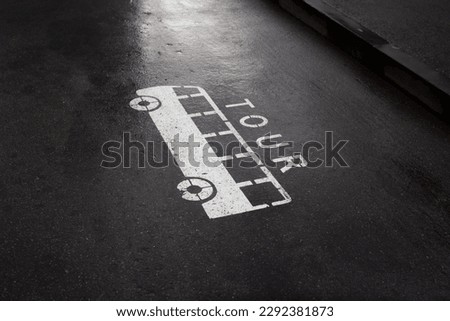 City photo. Road markings on asphalt of Georgian street in Tbilisi. White tourist bus sign with Tour text. Stencil on pavement. Concept of tourism, travel, adventure, sightseeing. Urban view. Symbol