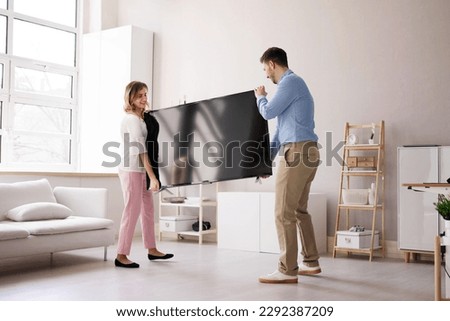 Smiling Young Couple Carrying New Television At Home Royalty-Free Stock Photo #2292387209