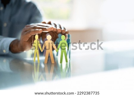 Inclusion, Diversity And Equality. African Hands Safeguard Wooden pawns Royalty-Free Stock Photo #2292387735