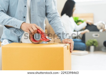 family relocation to new place concept, close up hands of person using tape packing cardboard of belonging stuff preparation to moving out relocation.