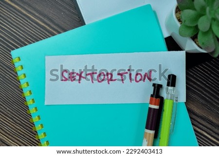 Concept of Sextortion write on sticky notes isolated on Wooden Table.