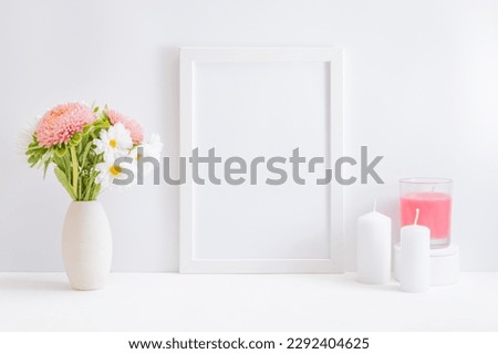 Home interior with decor elements. Mockup with a white frame white and pink flowers in a vase on a light background
