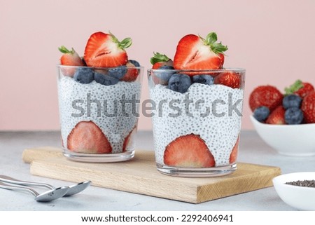 Chia pudding with strawberries and blueberries, chia seeds on a pink background. Healthy breakfast rich in protein - chia seed pudding, coconut milk and strawberries.  Royalty-Free Stock Photo #2292406941
