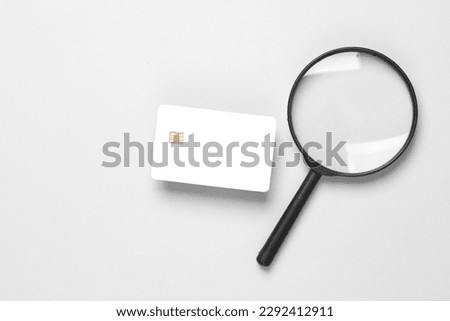 White empty bank card with a chip and a magnifier on a sermo background