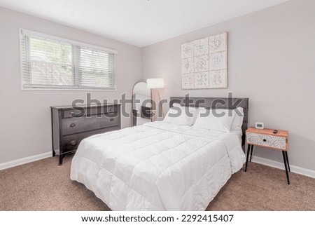 Wide angle photo of small bedroom with window, sofa, bed, wall picture, floor lamp, table, closet, tv