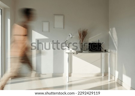 Man walking in apartment with minimalistic interior, blurred motion