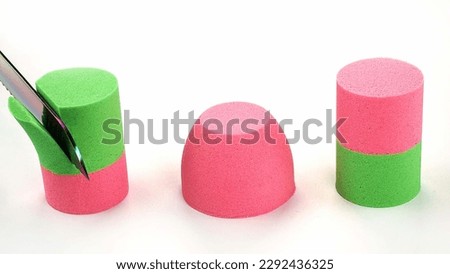Cutting kinetic sand with a knife on a white background. Royalty-Free Stock Photo #2292436325