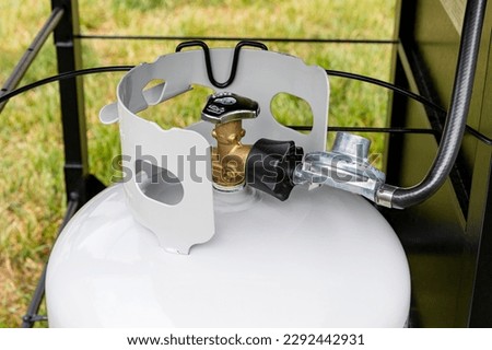 Propane gas cylinder with hose and regulator for BBQ grill. Grilling safety, LPG equipment inspection and storage Royalty-Free Stock Photo #2292442931