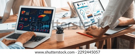 Panorama shot analyst team utilizing BI Fintech to analyze financial report with laptop. Businesspeople analyzing BI power dashboard displayed on laptop screen for business insight. Scrutinize