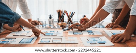 Panorama shot of front-end developer team brainstorming UI and UX designs for mobile app on paper wireframe interface. User interface development team planning for user-friendly UI design. Scrutinize Royalty-Free Stock Photo #2292445221