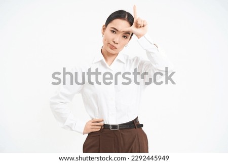 Successful businesswoman looks confident, shows L letter, loser sign on forehaed, feels proud of herself, smiles pleased over white background.