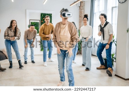 One woman mature senior caucasian female in front of group of men and women friends enjoy virtual reality VR headset at work having fun together during team building seminar real people bright filter Royalty-Free Stock Photo #2292447217
