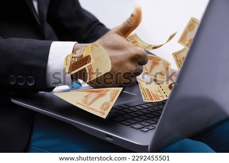 Venezuelan bolivar notes coming out of laptop with Business man giving thumbs up, Financial concept. Make money on the Internet, working with a laptop