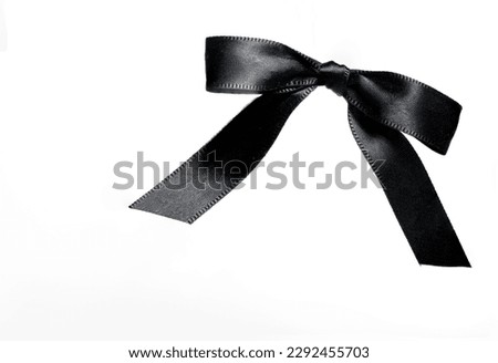 black noble bow loop mesh of black shiny wide ribbon on white background as a concept for mourning loss funeral condolence death commiseration and passing away