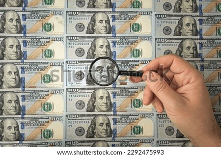 100 dollar bill and magnifying glass on white. man's hands hold dollars and magnifying glass. verification of the authenticity of the American banknote. search for counterfeit bills