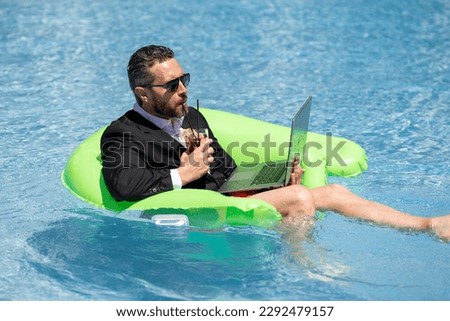 Summer business dreams. Business man in suit floating with cocktail and laptop in swimming pool. Summer business vacation. Funny crazy businessman rest in formal wear in pool. Hot summer business. Royalty-Free Stock Photo #2292479157