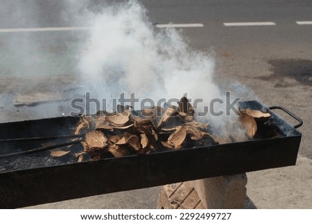 the process of burning coconut shells, which will produce coal as an ingredient for making grilled chicken.

