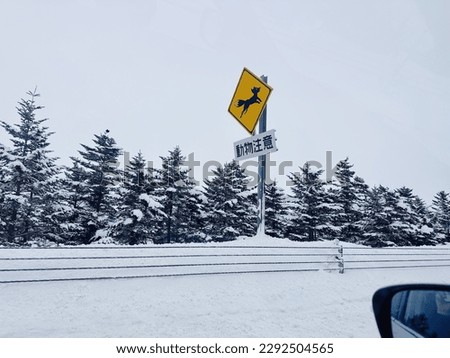 yellow and black road sign with the symbol of a fox and the text Slow down. Wildlife crossing caution sign. Concepts: eco tourism, nature protection. Japanese letters: Beware animals crossing