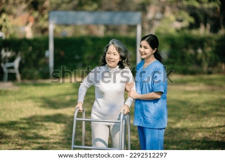 Asian young caregiver nurse support senior older male walking outdoors. Specialis doctor help and take care of elderly mature. Nursing home hospital garden concept.

 Royalty-Free Stock Photo #2292512297
