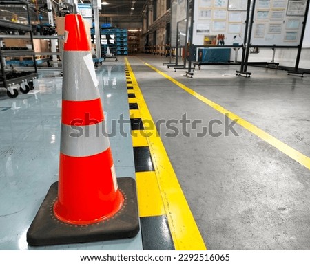 Red cones stand beside the walkway sign and are painted yellow on the factory floor. industrial safety sign