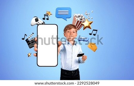 Smiling child with mock up phone and credit card in hand, diverse entertainment icons, video games, streaming music and photos. Concept of online shopping, fun and mobile app