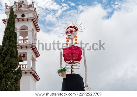 Mazamitla, Jalisco, Mexico; October, 23, 2022: Huge catrina built for the celebration of the day of the dead, white church in the background. Royalty-Free Stock Photo #2292529709