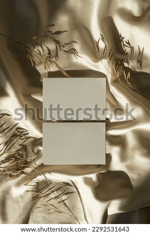 Blank paper sheet cards with mockup copy space on crumpled glossy gold silk cloth background with sunlight shadows silhouette. Aesthetic bohemian minimal business brand template. Flat lay, top view