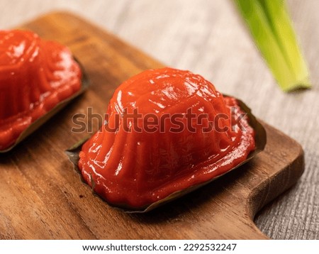 Kue Angku Kue Ku an Indonesian Traditional cake served on a wooden tray at wooden table. an oval shaped pastry with soft, sticky glutinous rice flour skin wrapped around a sweet central filling. Royalty-Free Stock Photo #2292532247