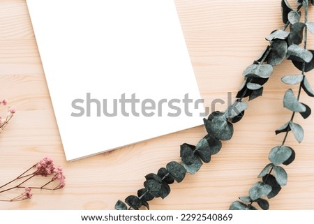 Empty white sheets with dried flowers on wooden table.