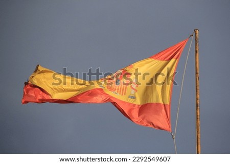 MADRID, SPAIN - JUNE 17, 2022: Spanish flag on the roof of a house against a dark sky background, Madrid. flag in the hands of an angel sculpture.