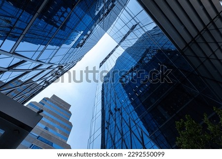Bottom view of modern skyscrapers in business district against blue sky. Worm's-eye view architecture and blue background