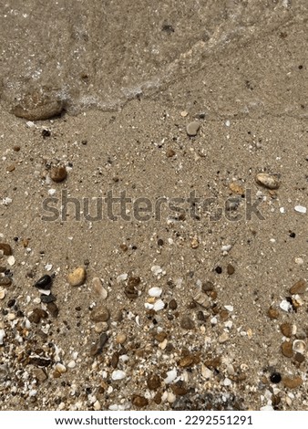 Pebbles and shells on sandy beaches with sea water.