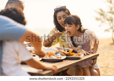 Happy Multi-Generation Asian family having celebration dinner food and drink together at tropical beach restaurant during travel ocean on summer holiday vacation at sunset. Family relationship concept Royalty-Free Stock Photo #2292551325