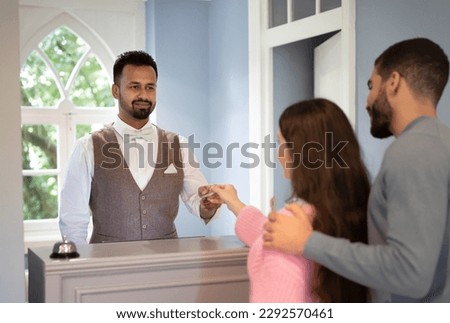 Indian Receptionist Man Taking Credit Card From Guests Couple Receiving Payment For Accomodation Standing At Counter In Resort Lobby Indoor. Tourists Paying For Room In Hostel. Selective Focus Royalty-Free Stock Photo #2292570461